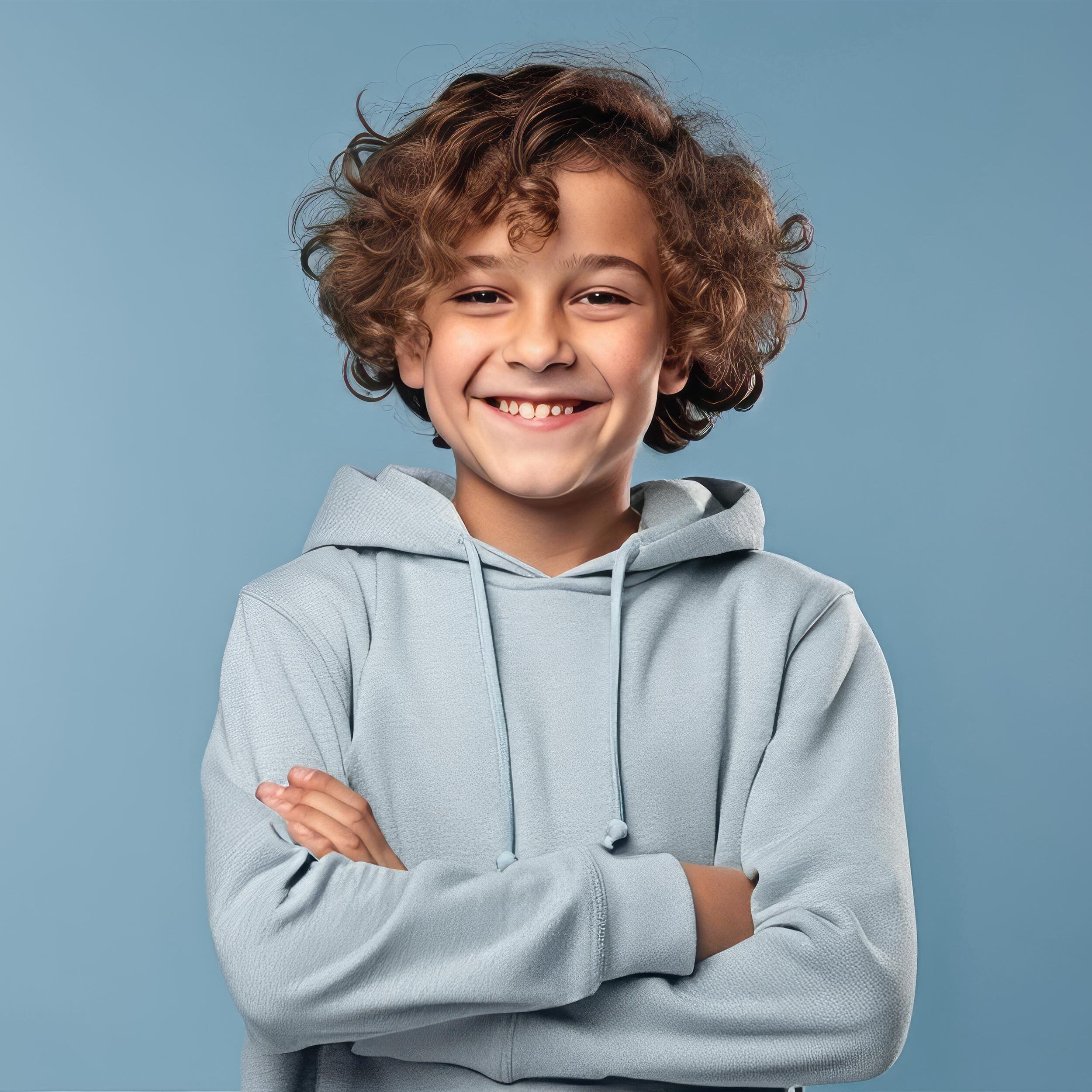A happy boy with curly hair wearing a blue hoodie, smiling after receiving root canals.